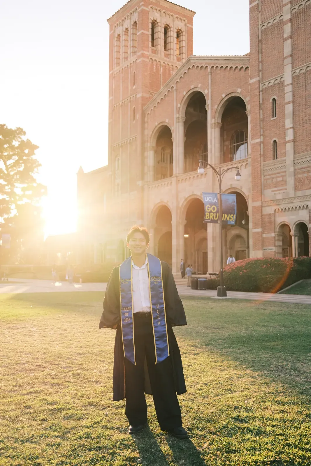 Phuc Truong at UCLA graduation in front of Royce Hall at golden hour, wearing a Class of 2026 Mathematics of Computation stole